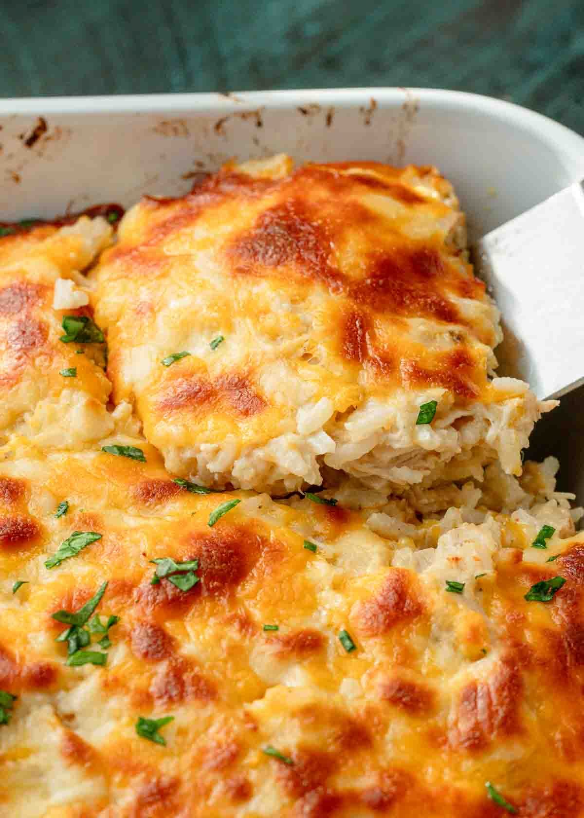 a piece of easy chicken and rice casserole topped with cheese and fresh herbs