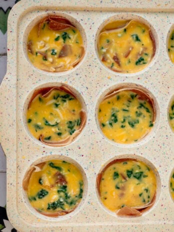 a standard muffin pan filled with spinach egg bites