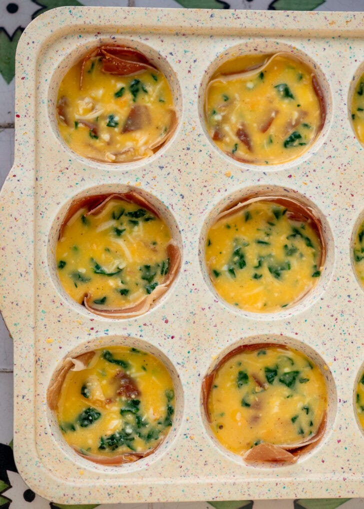 a standard muffin pan filled with spinach egg bites