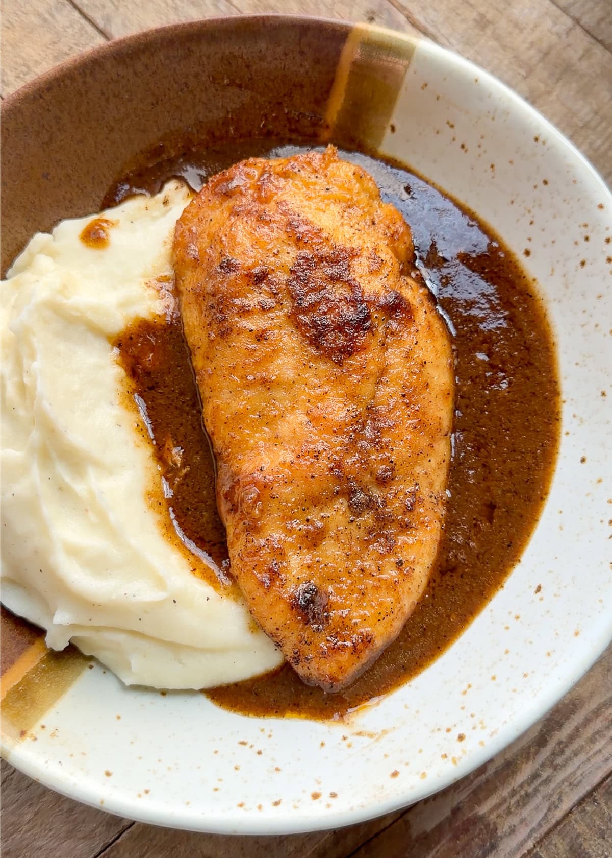 chicken and gravy in a shallow bowl with mashed potatoes
