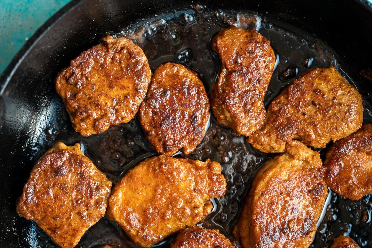 pork medallions being cooked in cast iron skillet