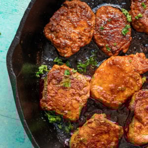 overhead image of pork medallions being garnished in cast iron skillet