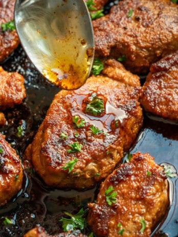 overhead image of white wine sauce being spooned onto pork medallions