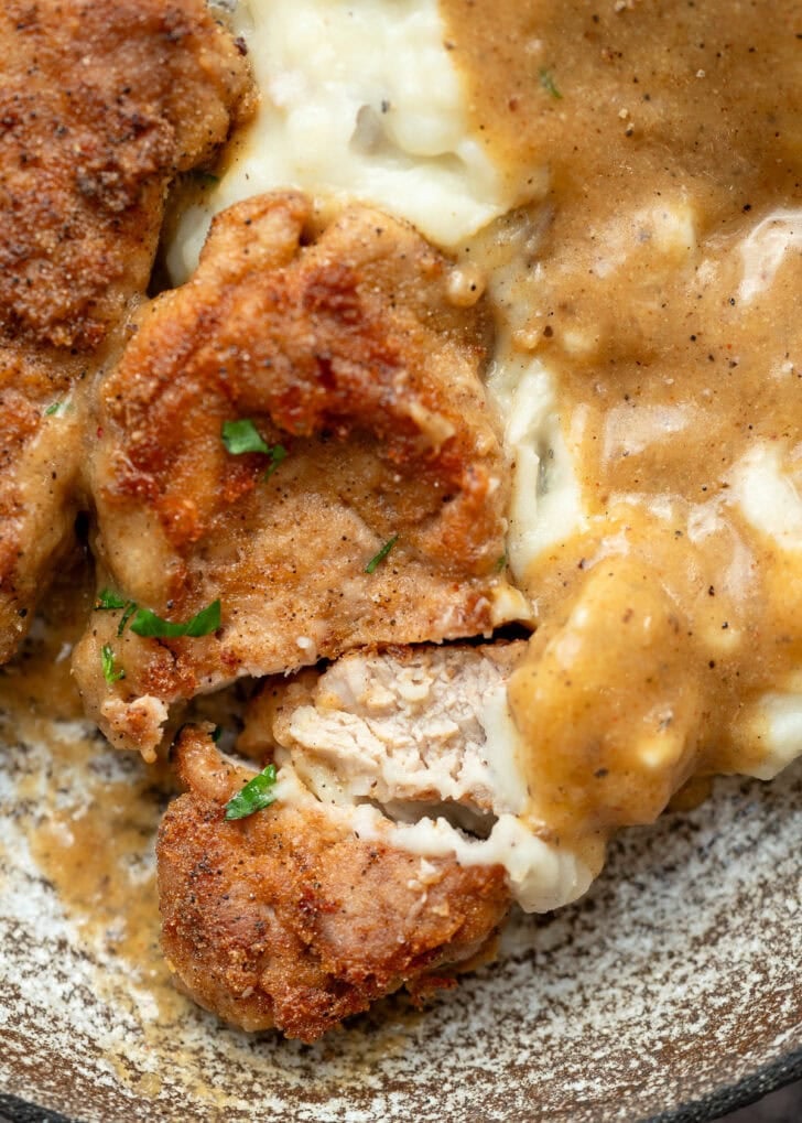 juicy fried pork tenderloin cut up to eat with mashed potatoes and gravy