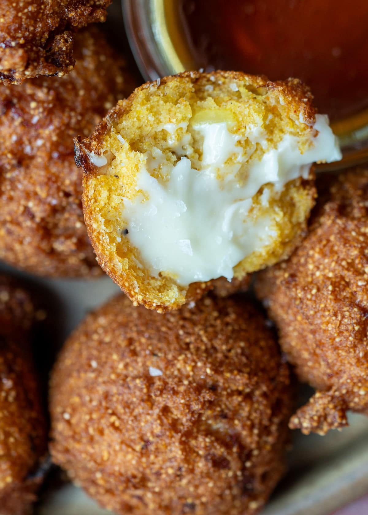 whipped butter on a hush puppy beside a side of hot honey