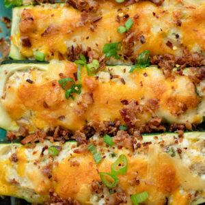 several chicken bacon ranch zucchini boats lined up garnished with green onions and bacon