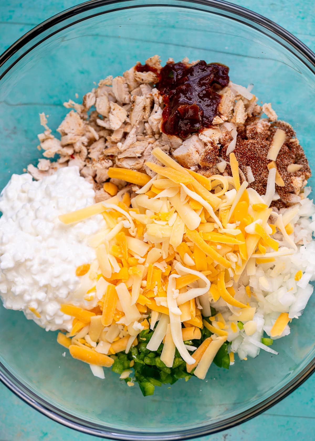 shredded chicken in a bowl with cheese, cottage cheese, diced onion, diced jalapeno, chipotle pepper, and adobo sauce