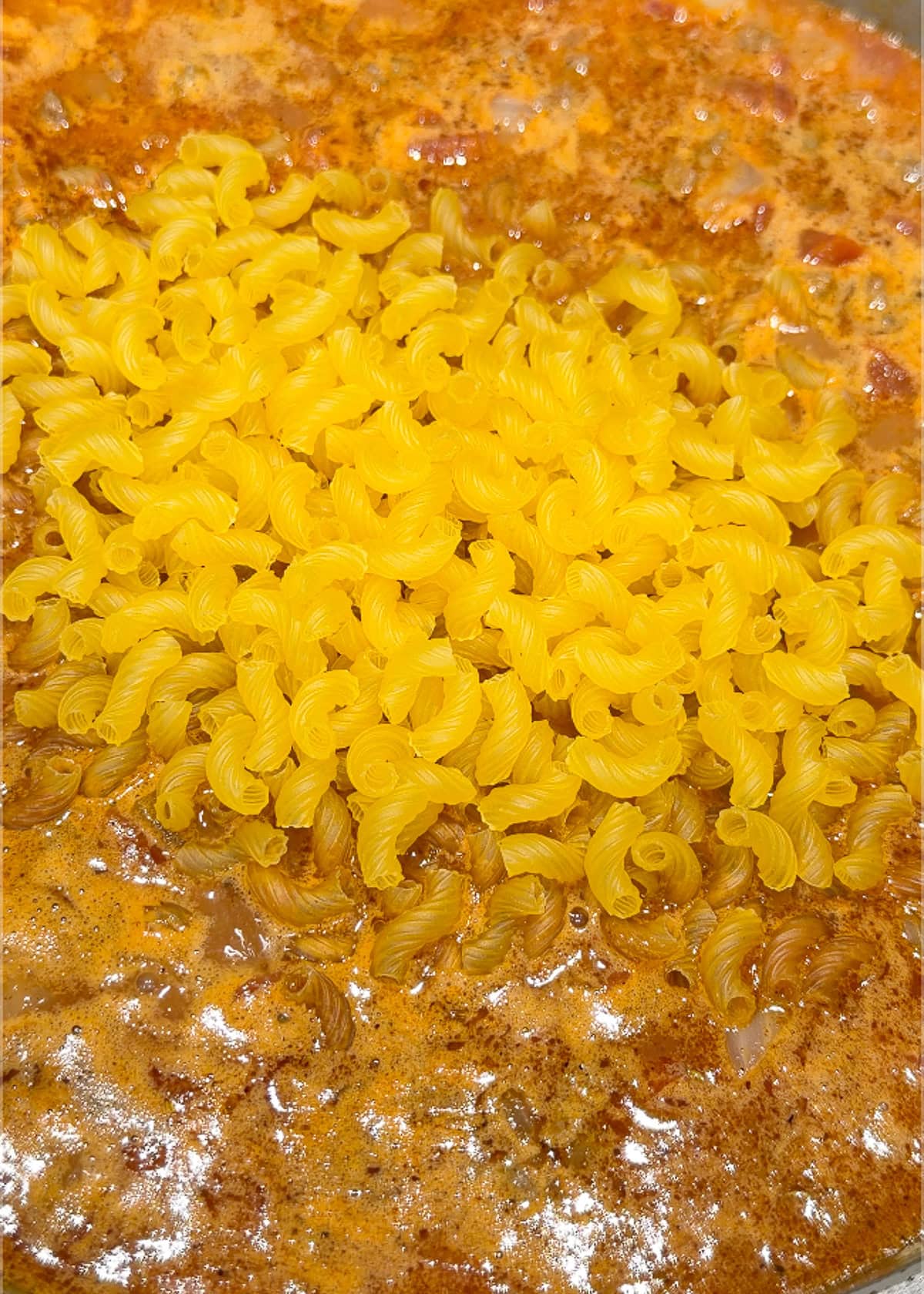 a creamy ground beef mixture in a skillet with macaroni noodles added
