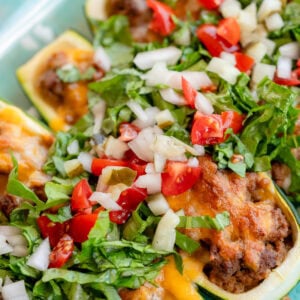 a baking dish full of ground beef zucchini boats topped with cheeseburger filling
