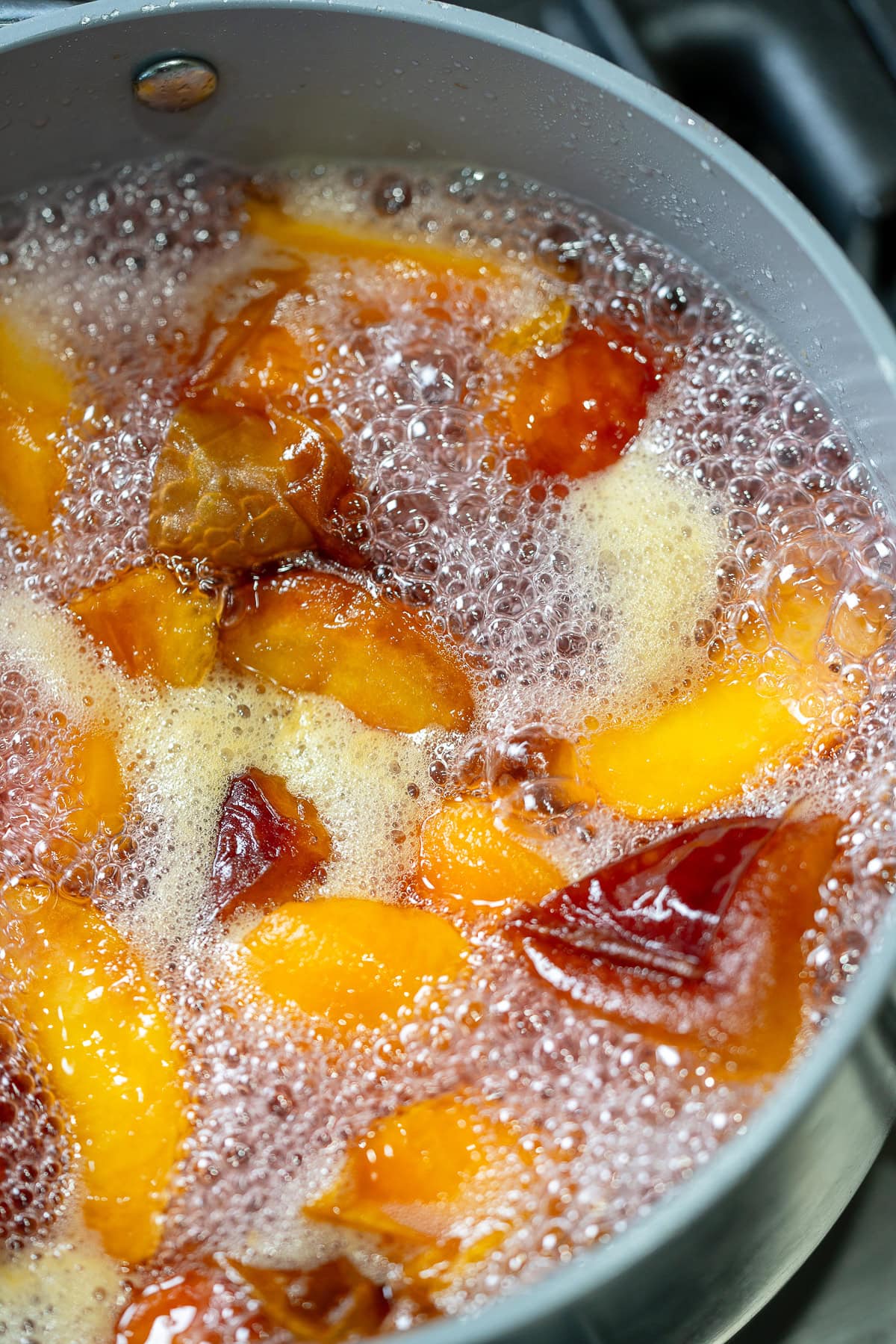 quartered peaches simmering in a simply syrup in a pot