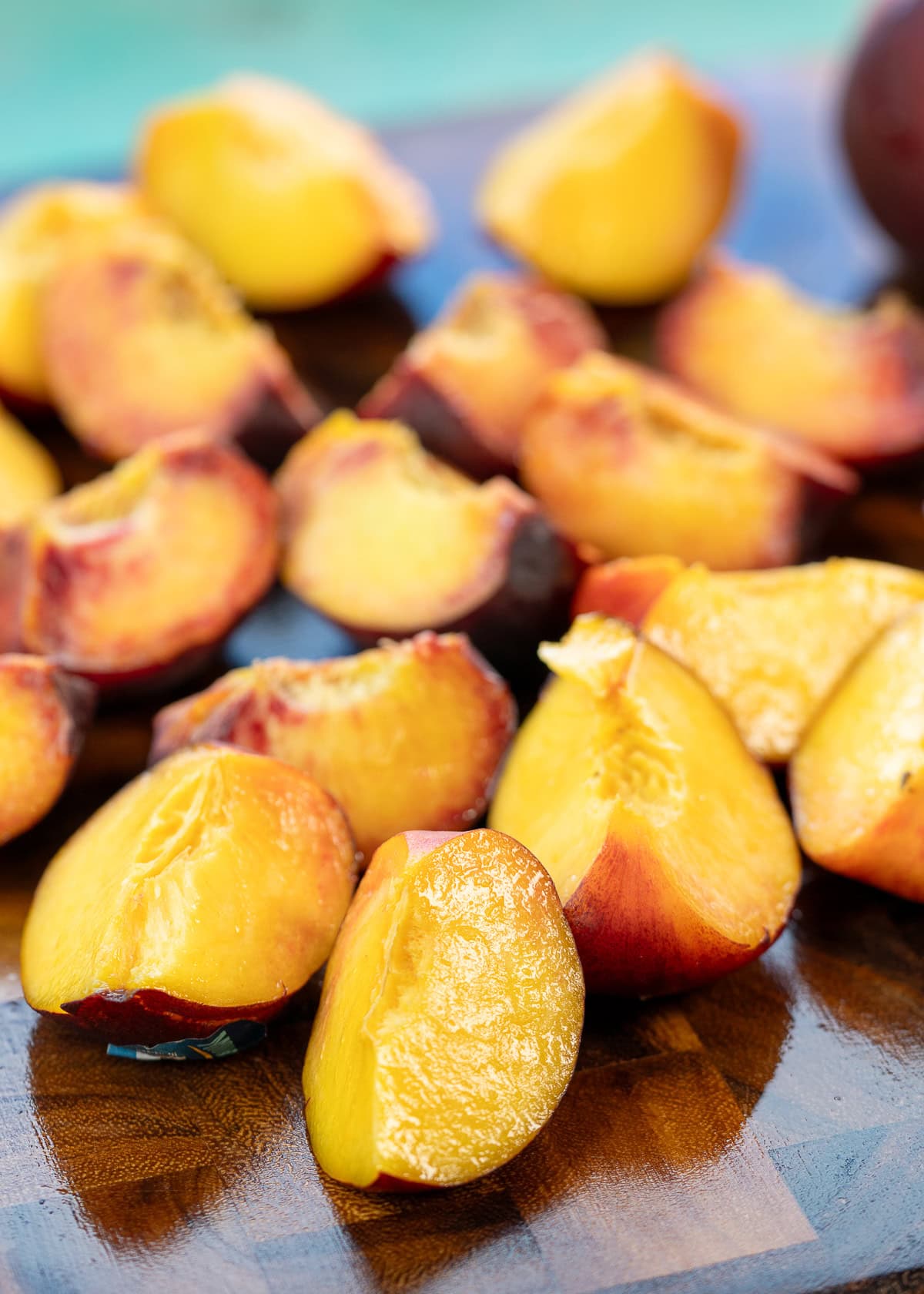 peaches sliced into quarters on a cutting board