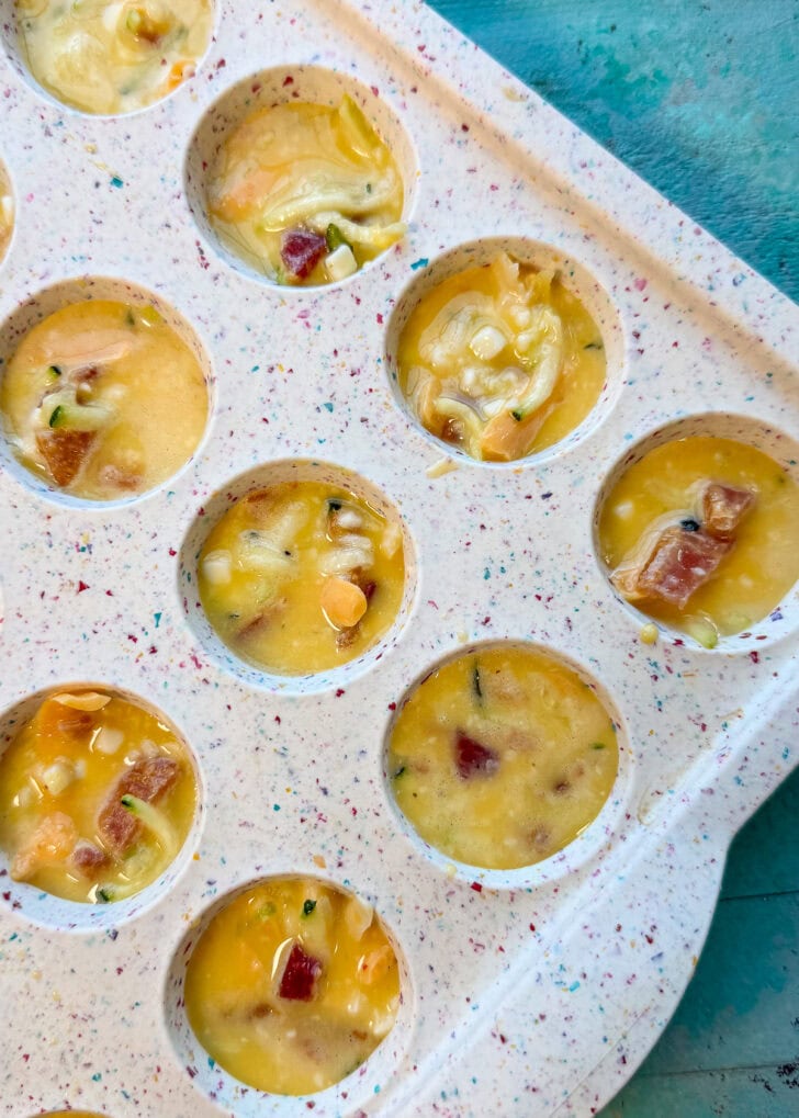 silicone muffin pan filled with zucchini egg bite mixture