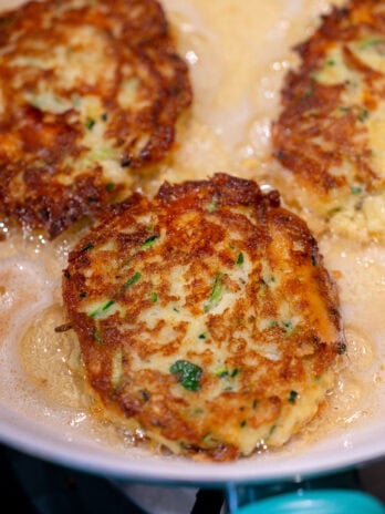 zucchini fritters frying in a pan