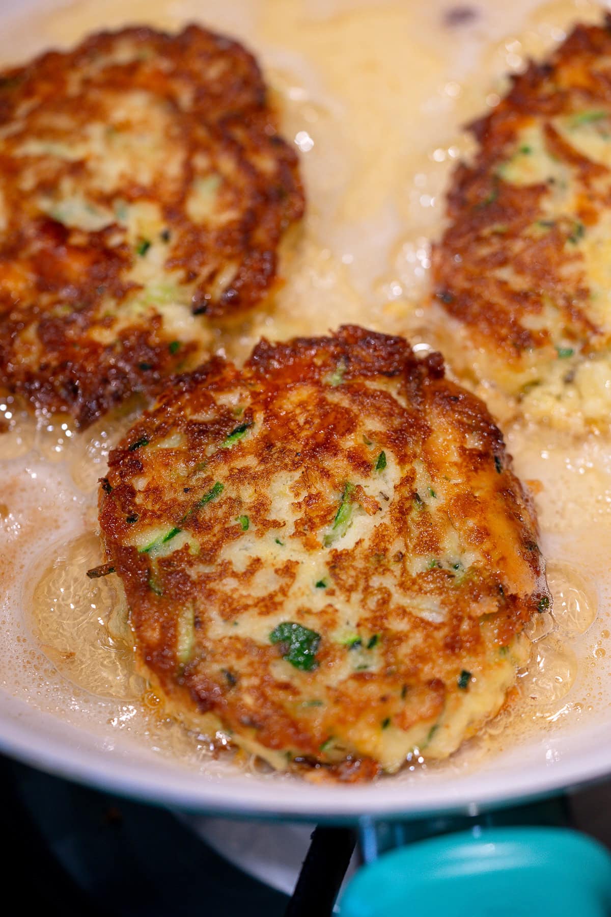 zucchini fritters frying in a pan