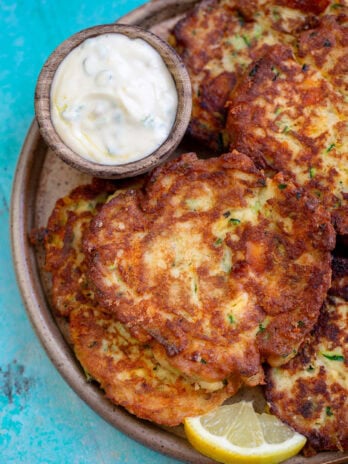 easy keto zucchini fritters on a platter with a lemon wedge and dipping sauce