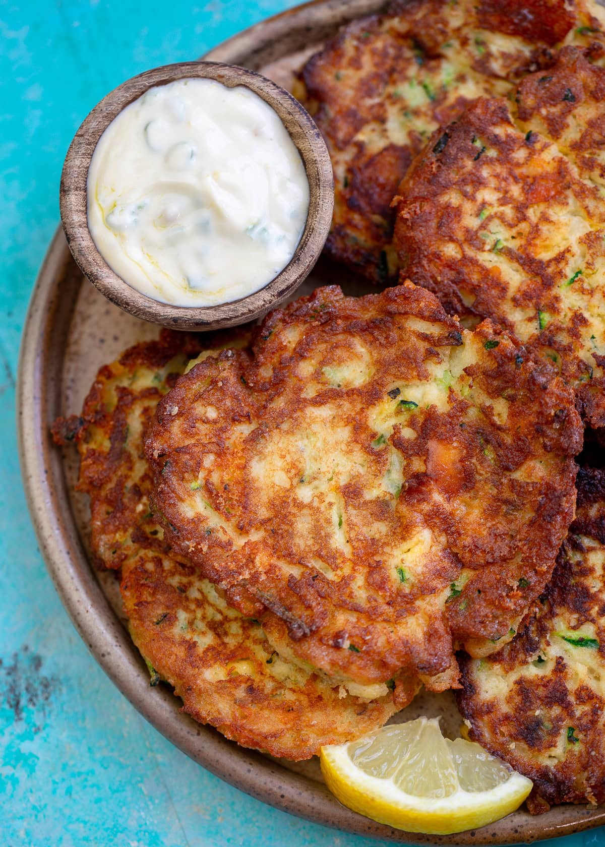 easy keto zucchini fritters on a platter with a lemon wedge and dipping sauce