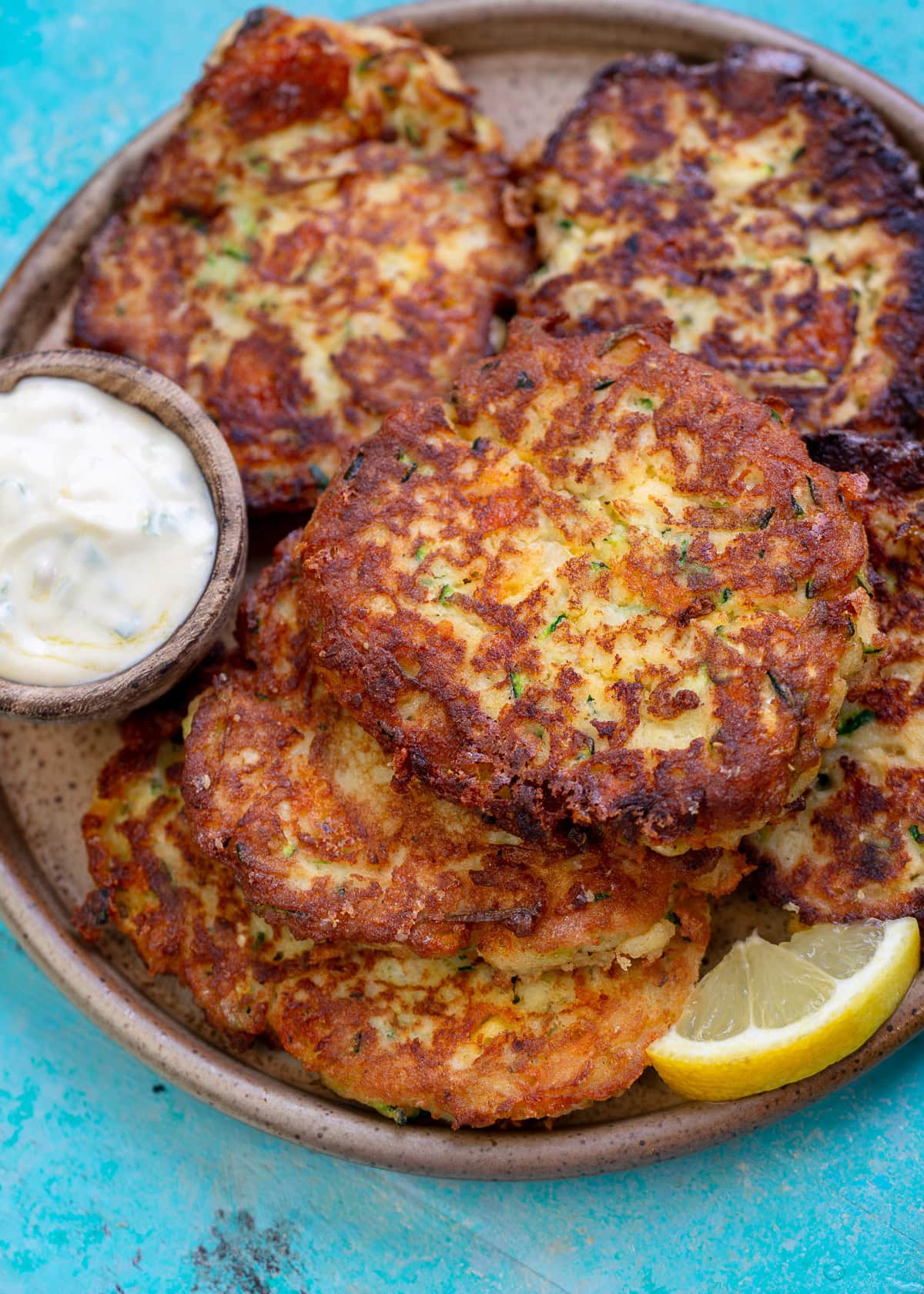 a platter full of crispy zucchini fritters with dipping sauce