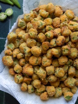 overhead shot showing golden brown pan fried okra in a bowl lined with paper towels
