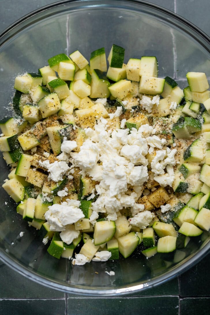 uncooked zucchini, spices and feta in a bowl