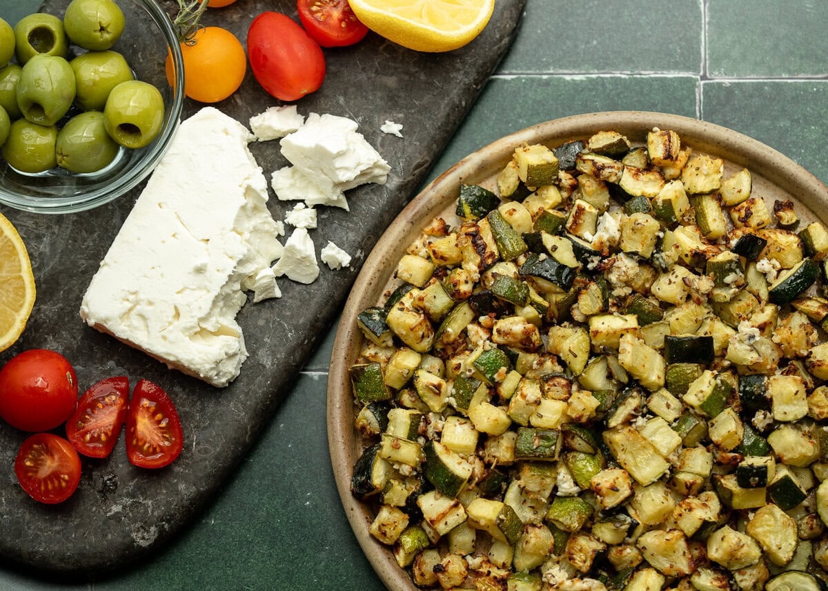 air fryer zucchini with feta on a green background