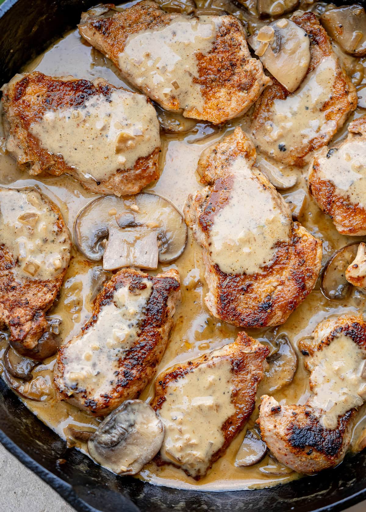 overhead shot of cast iron skillet full of pork medallions with mushroom gravy
