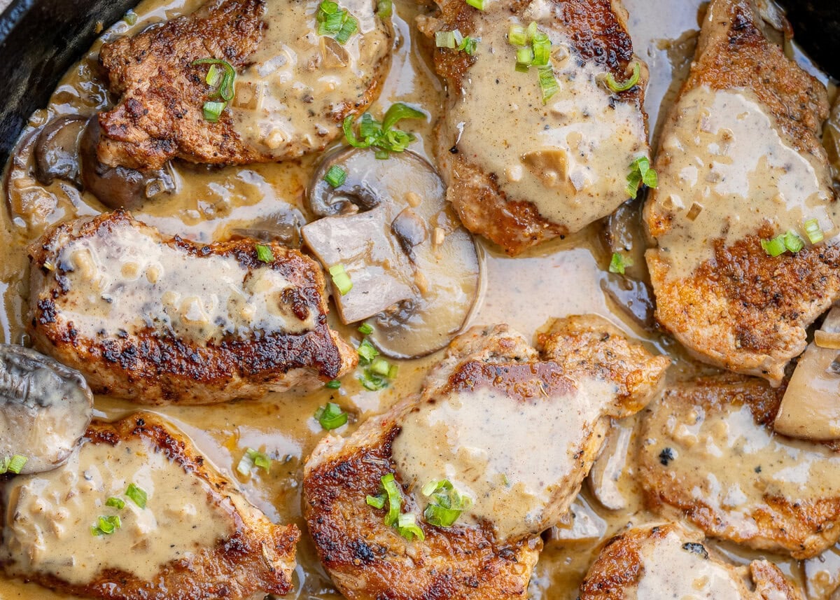 closeup image showing perfectly seared pork medallions with mushroom gravy in a skillet