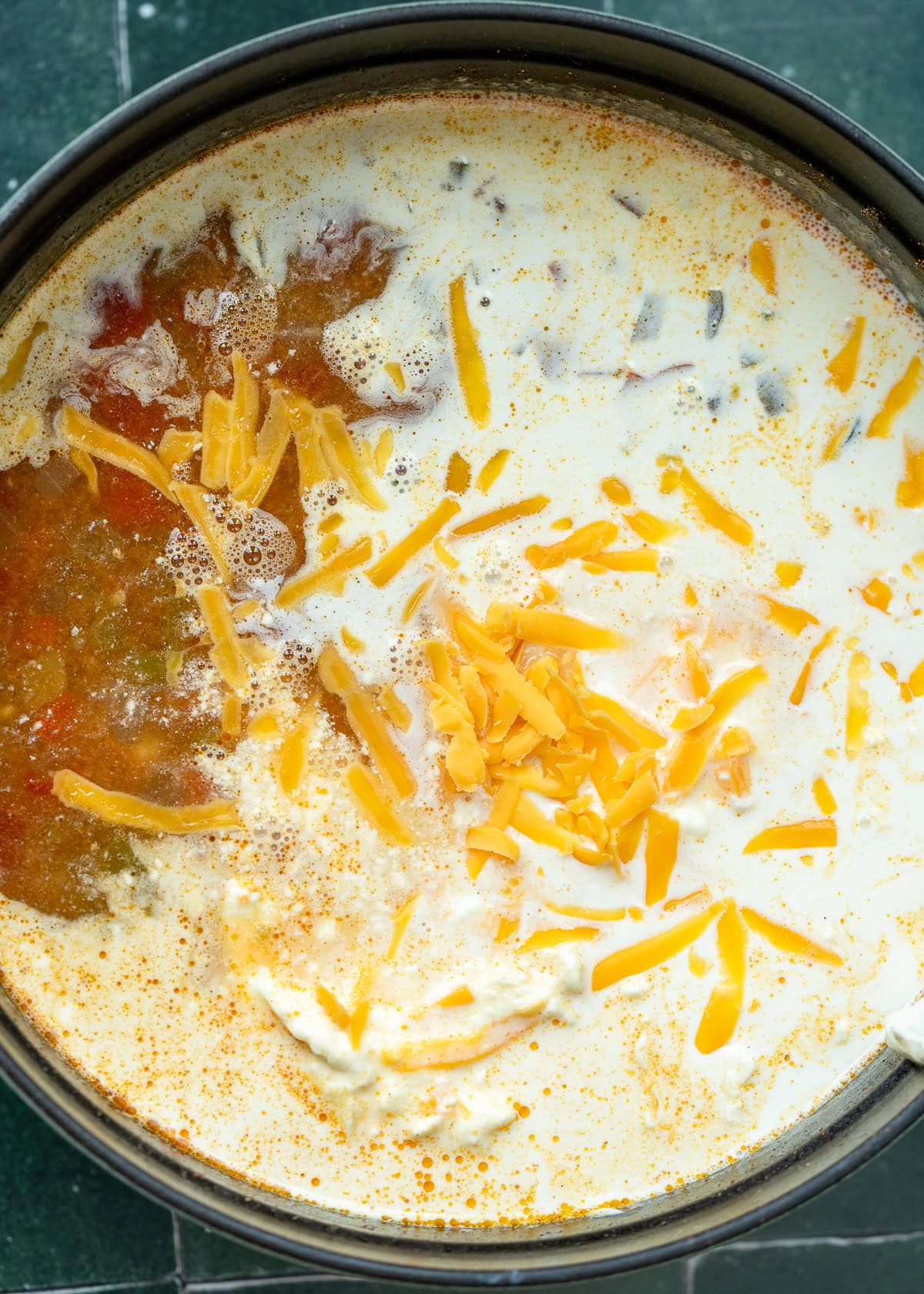 heavy cream, cream cheese, and shredded cheddar in a large pot of soup