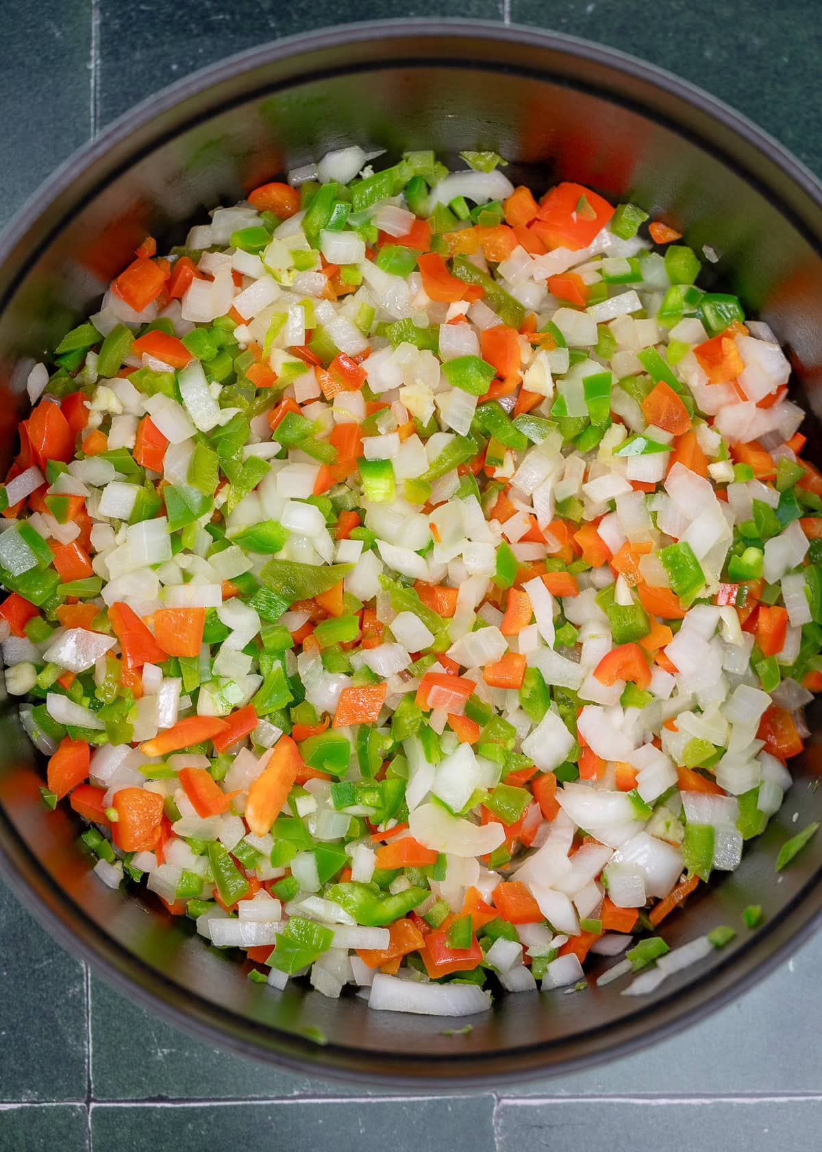 diced onion, bell peppers, and jalapenos cooking in a pot