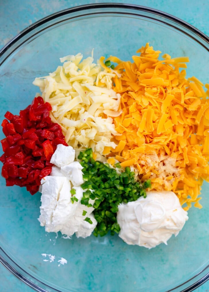 shredded cheeses, pimentos, jalapeno, mayonnaise, and cream cheese in a glass bowl