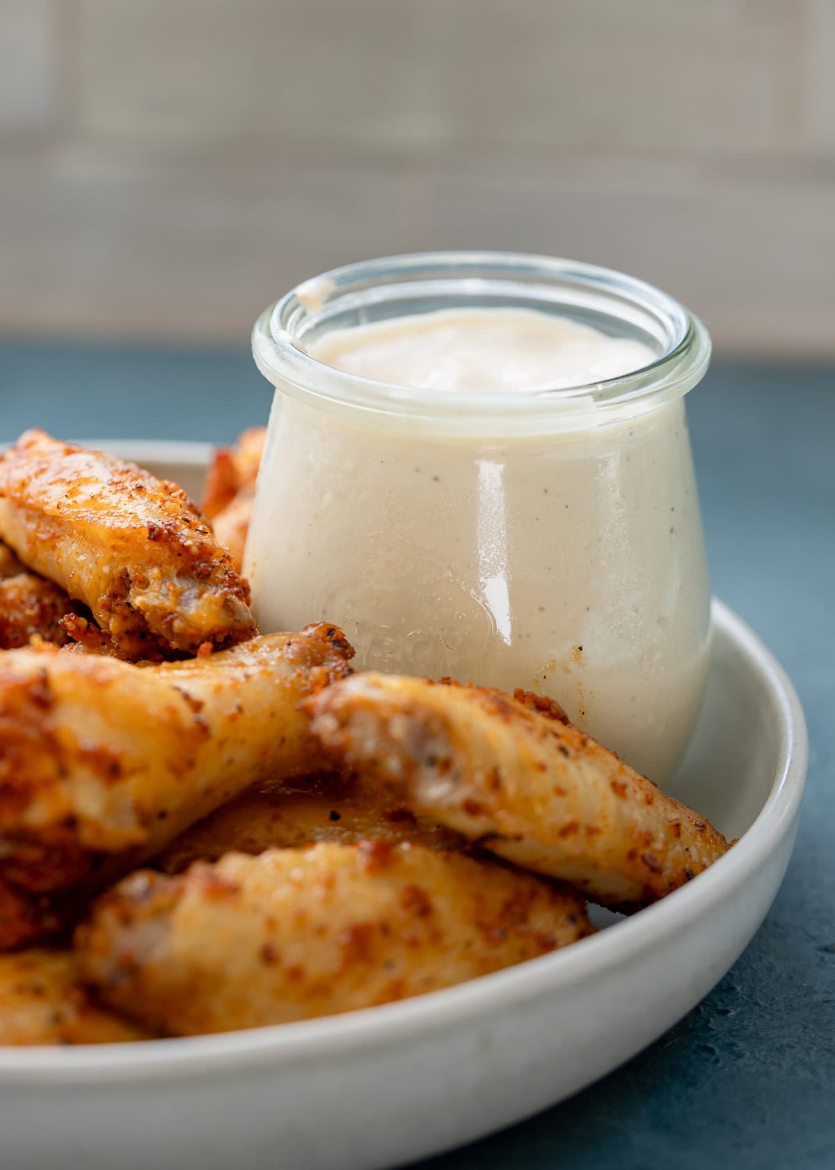 a jar of alabama white sauce on a platter with dry rub wings
