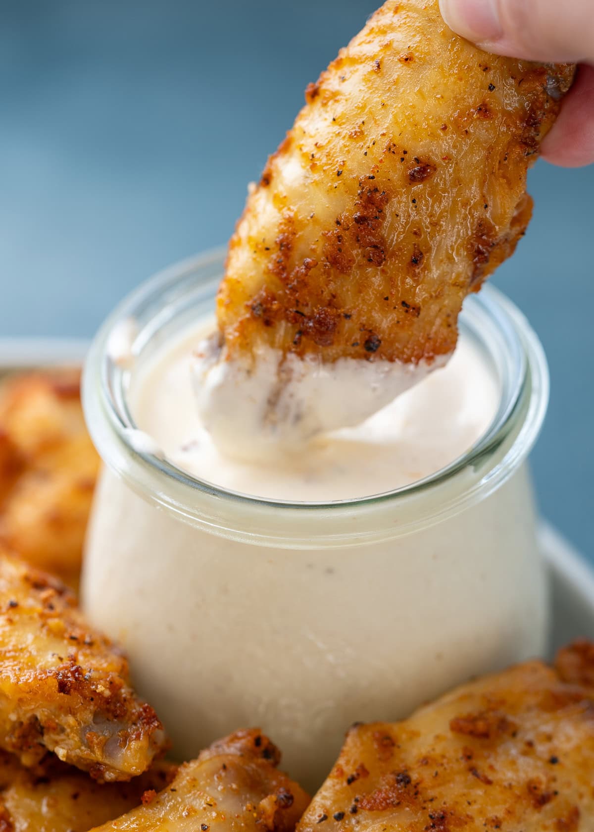chicken wing dipped into a jar of alabama white sauce