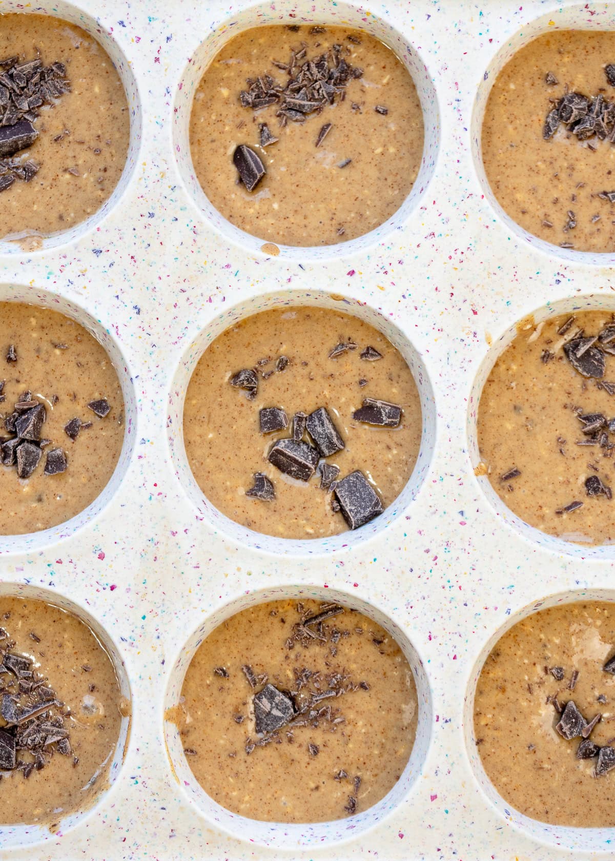 a standard silicone muffin pan filled with banana muffin batter and chocolate chips