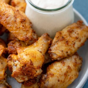 a plate full of dry rub chicken wings with a side of alabama white sauce