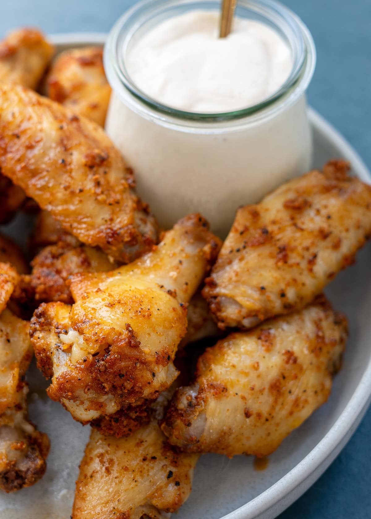 a plate full of dry rub chicken wings with a side of alabama white sauce