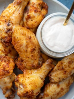 overhead shot showing crispy dry rub wings on a platter with dipping sauce