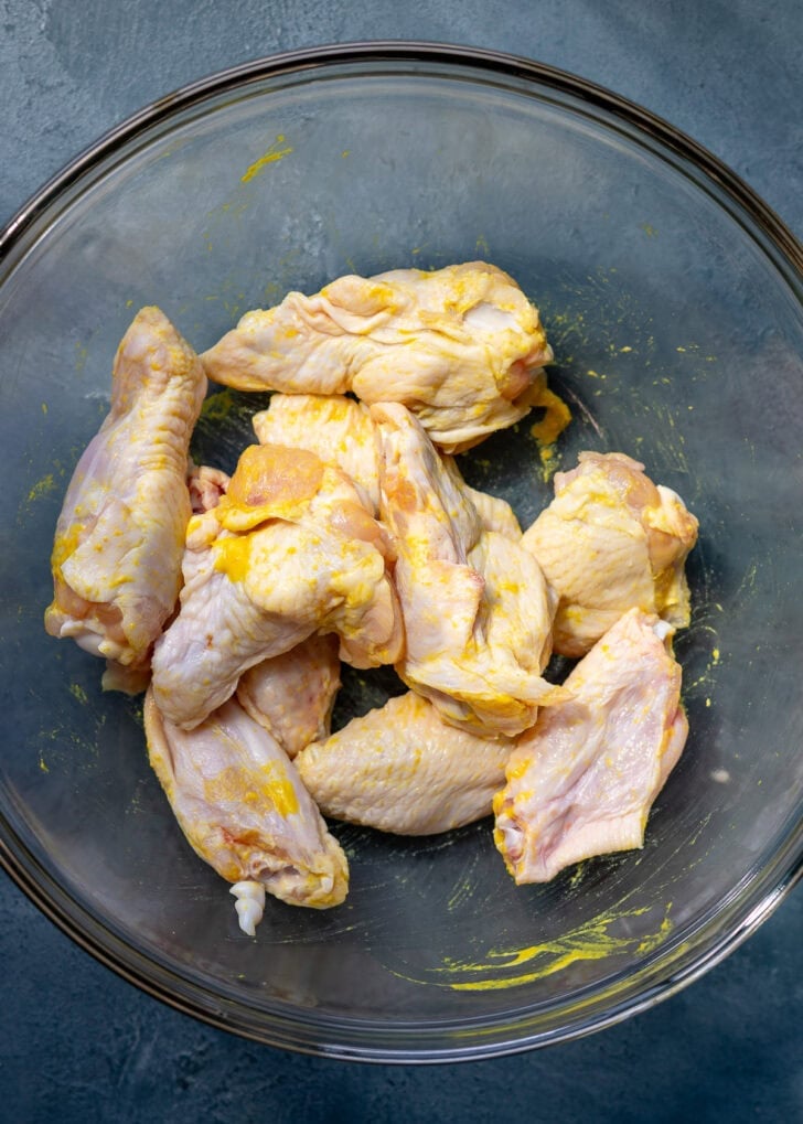 wings coated in mustard in a glass bowl
