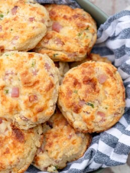 a basket full of cheesy gluten free muffins filled with cottage cheese, jam, and jalapeno